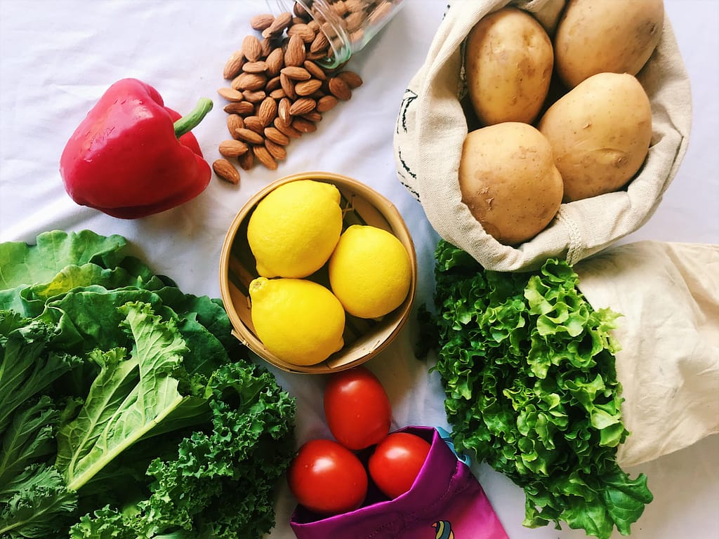 lettuce, tomatoes, lemons, potatoes, almonds on top of a white tablecloth