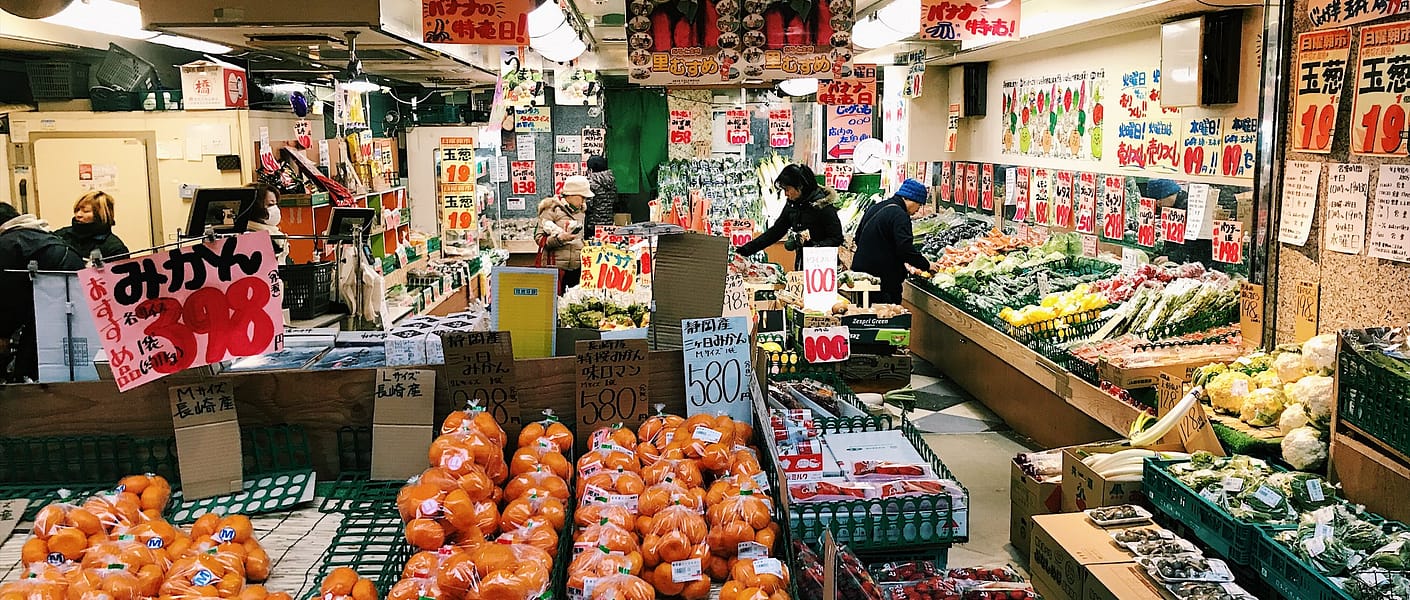 open market stall with veggies and fruits wrapped in plastic