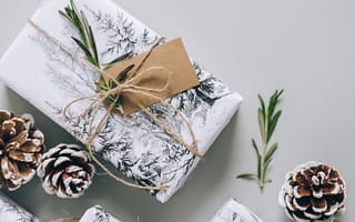 presents wrapped in white wrapping paper with brown tags, string, pinecones and greenery scattered around