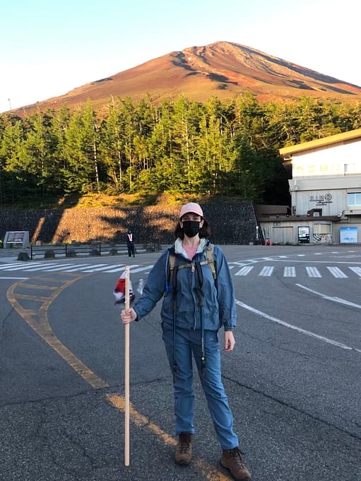 woman with hiking stick standing at base of mt fuji