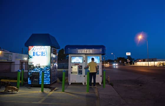 man standing in front of water dispensing machine under night sky